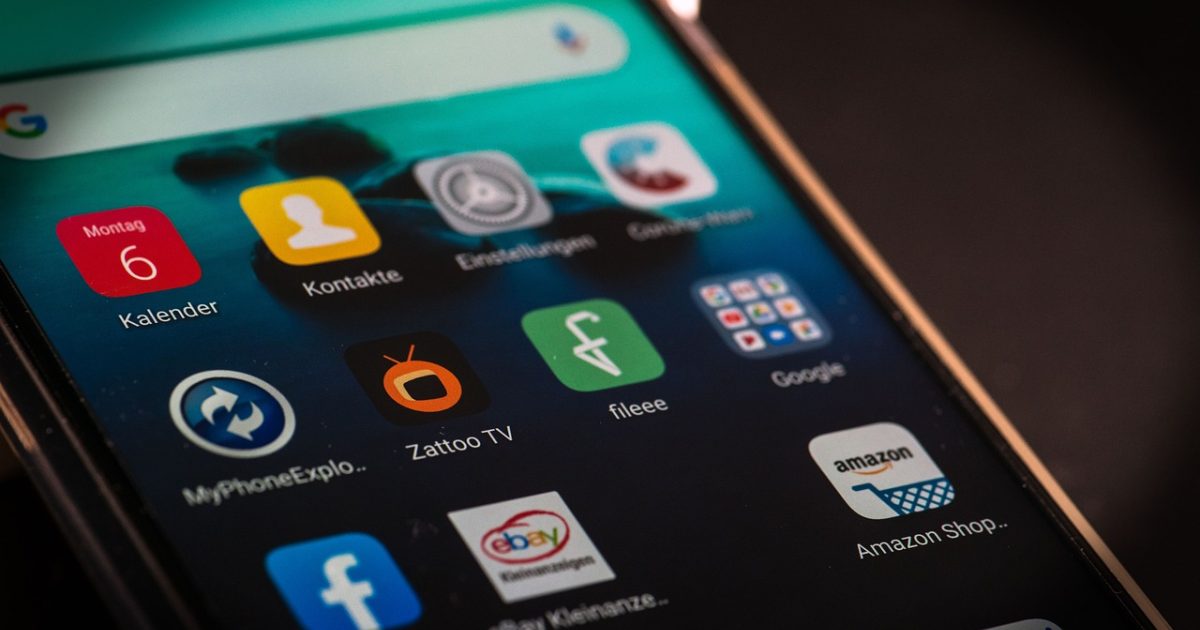 联想管家 App 主界面在手机屏幕上亮起，深色背景里几个圆形功能入口呈弧线排开，桌面壁纸是酒红与米金撞色的几何图案，整体氛围安静而克制